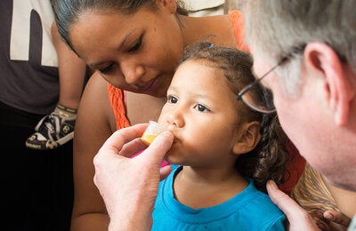 Enfermedades desatendidas, tropicales y transmitidas por vectores: niña bebiendo medicamento antiparasitario